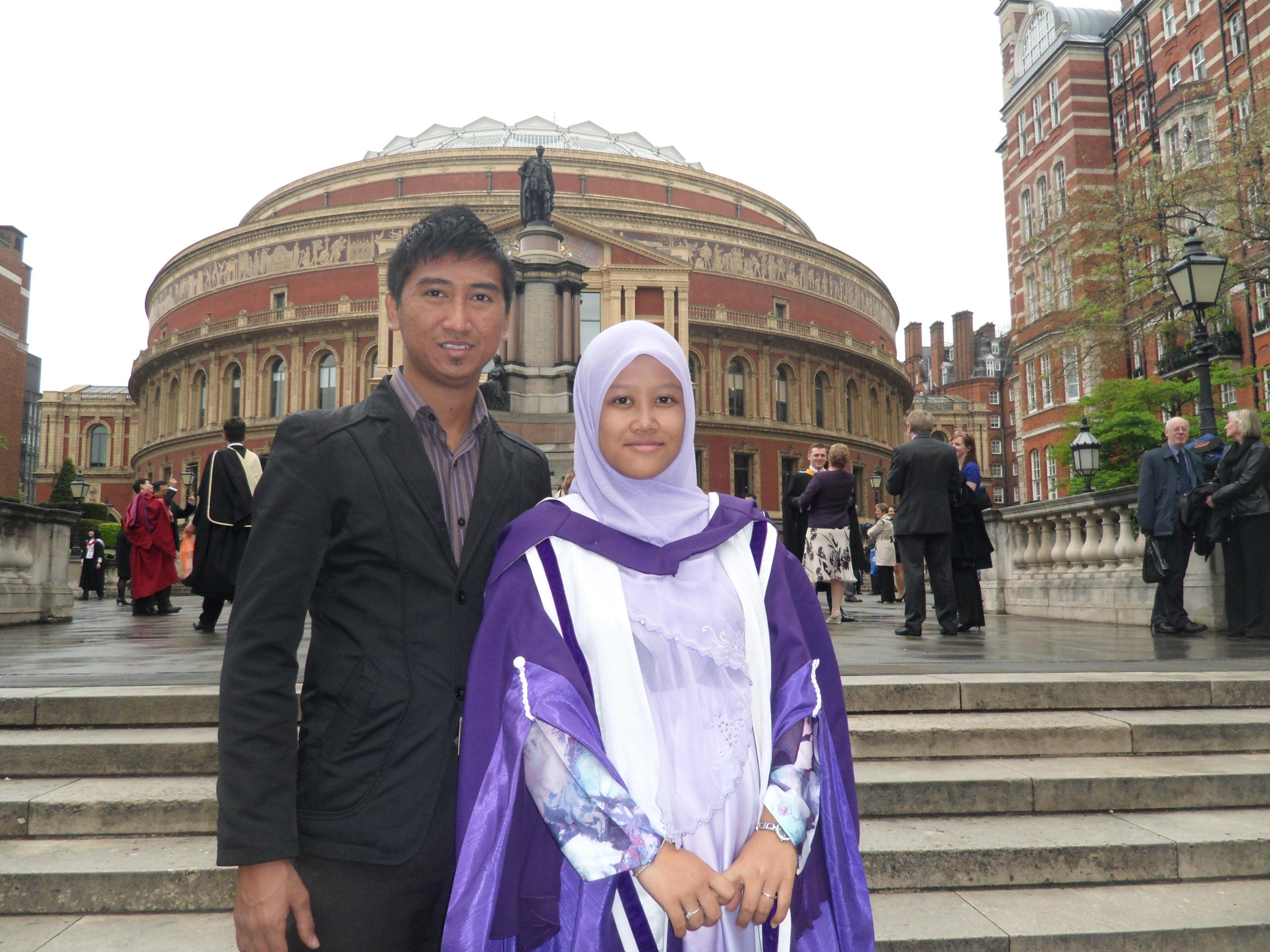 Maria in purple graduation robes outside the Royal Albert Hall with her husband