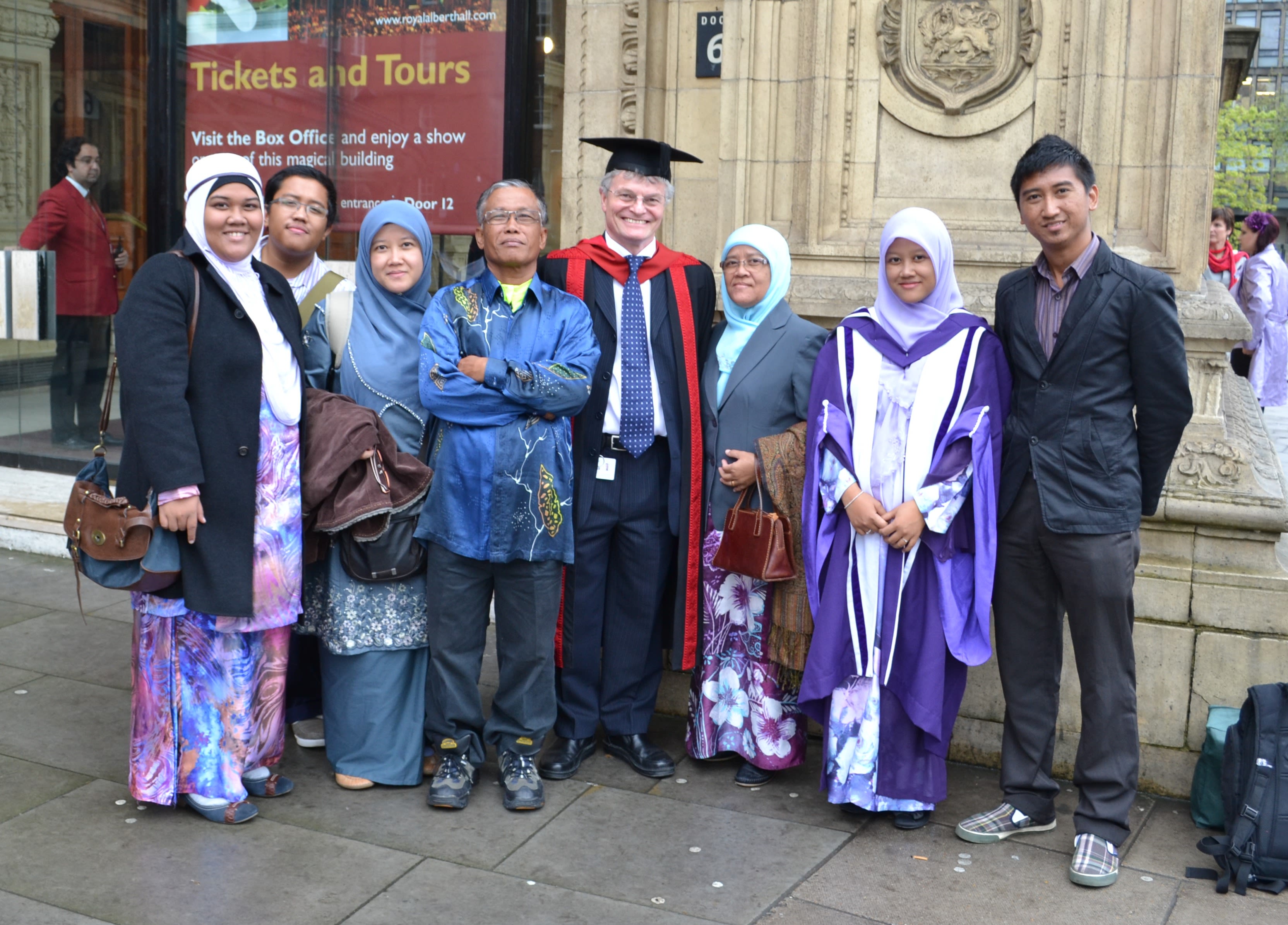 A group photo outside the Royal Albert Hall with Maria and Mike wearing graduation ceremonial robes