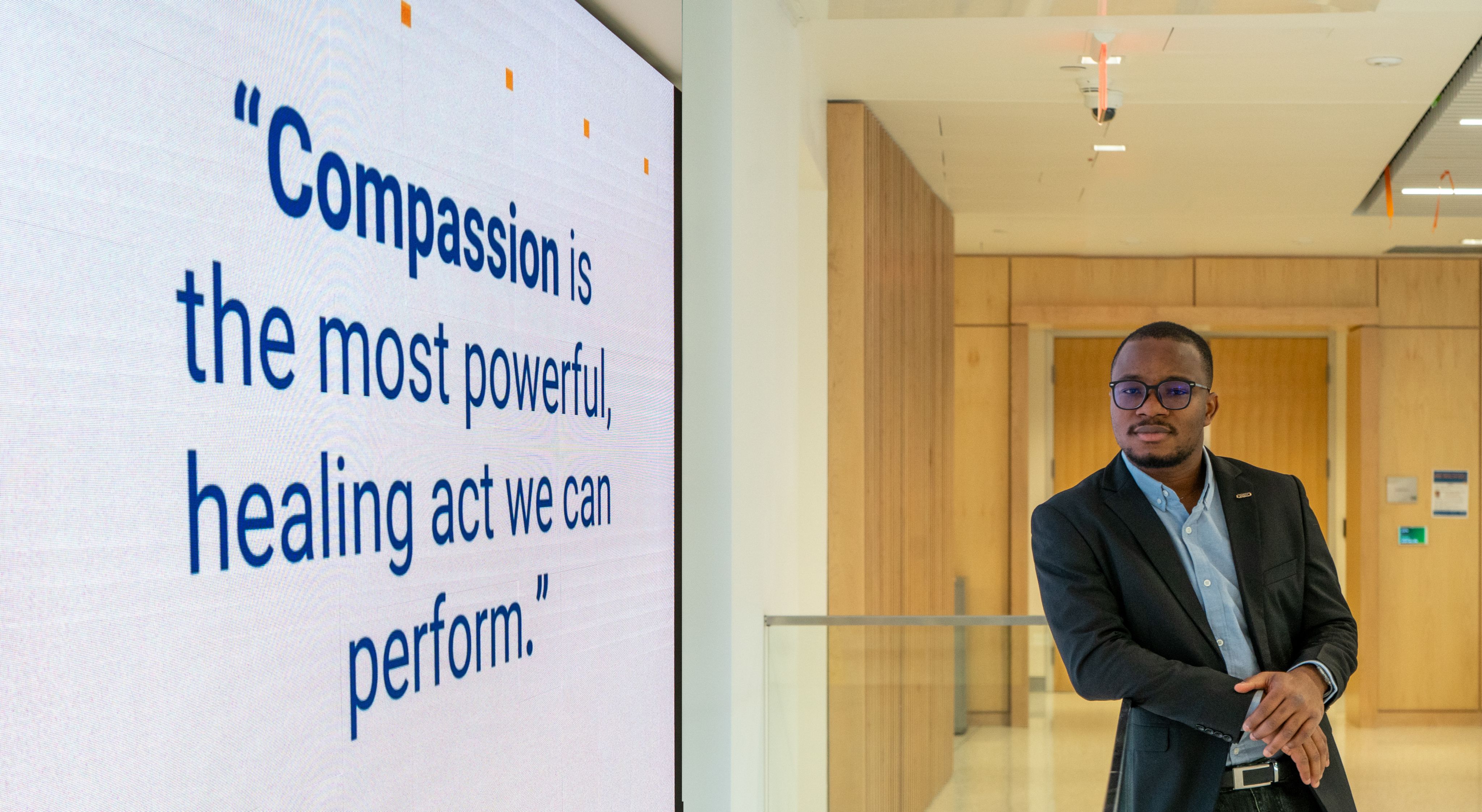 Tunde Oyebamiji stood by a sign that reads "Compassion is the most powerful, healing act we can perform."
