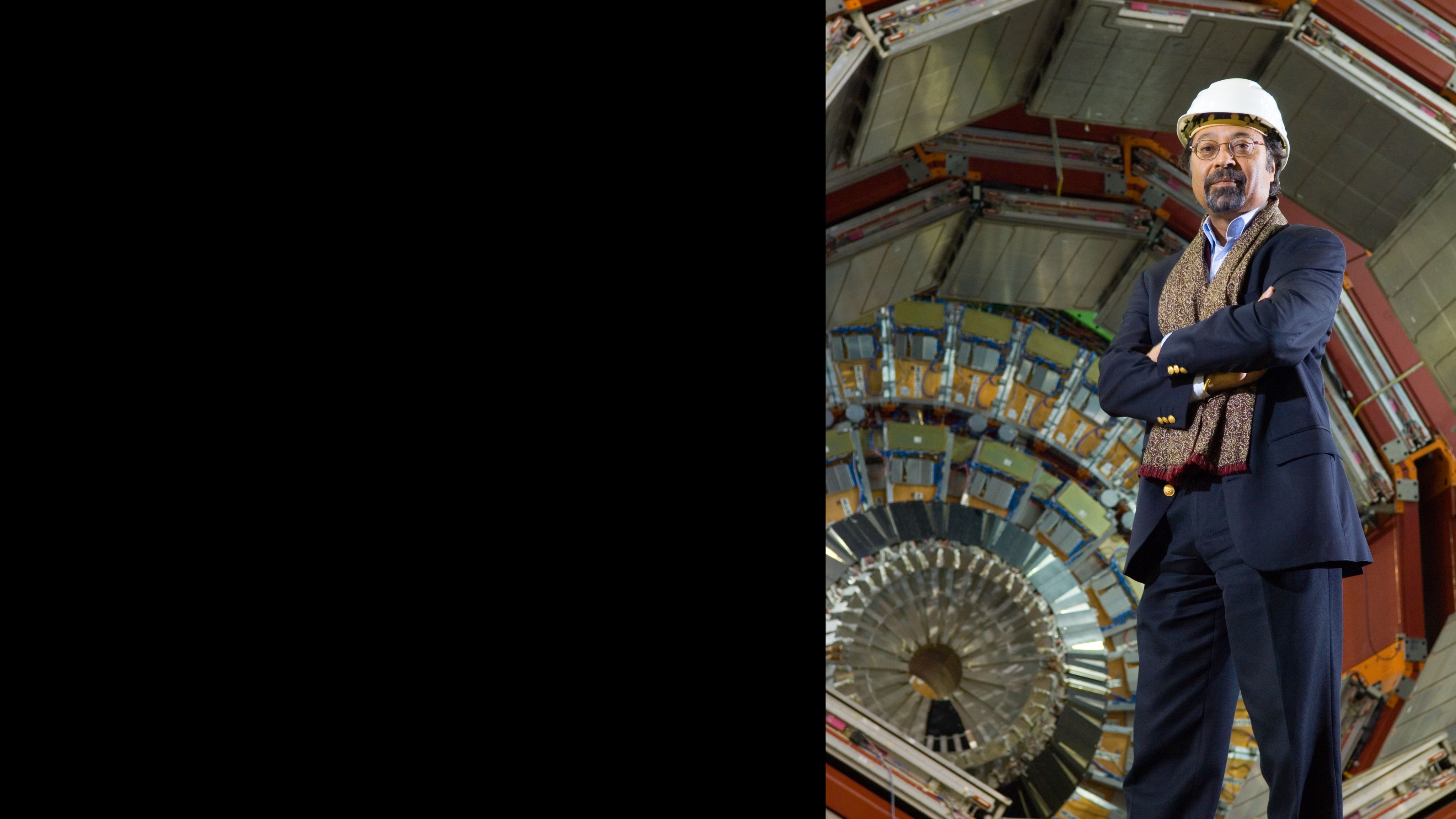 A photo of Jim Verdee, wearing a white hard hat, in front of the CMS detector.