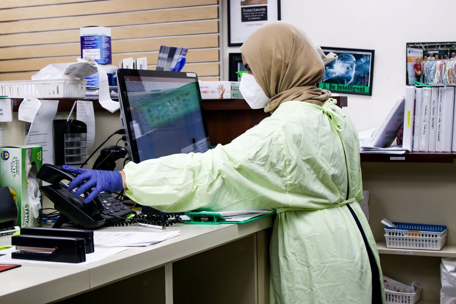 a person wearing a mask and gloves working on a computer
