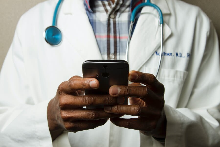 a person in a white coat using a mobile phone