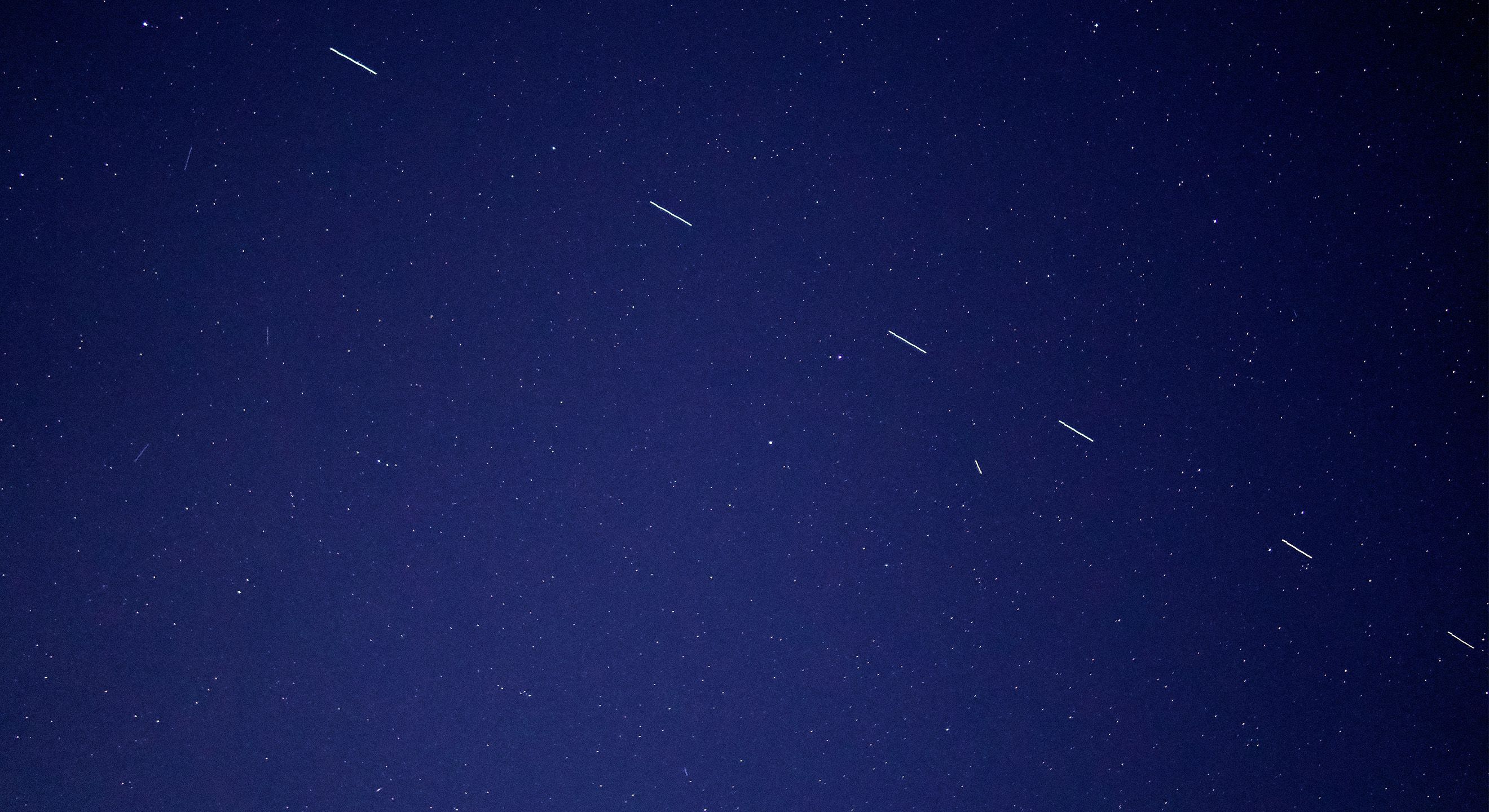 The dark sky at night with satellites and stars across the sky