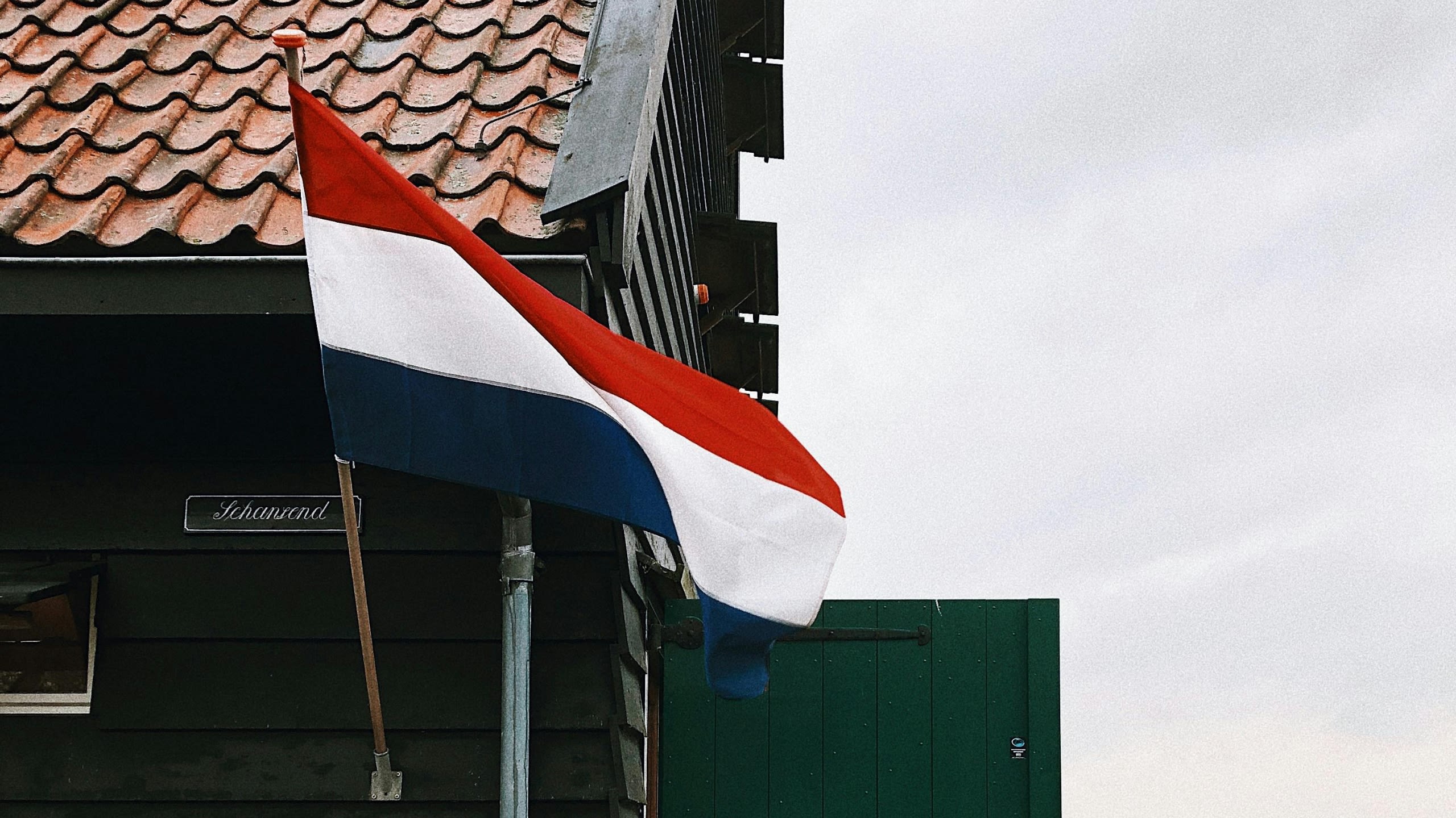 A Dutch flag blowing in the wind outside a house