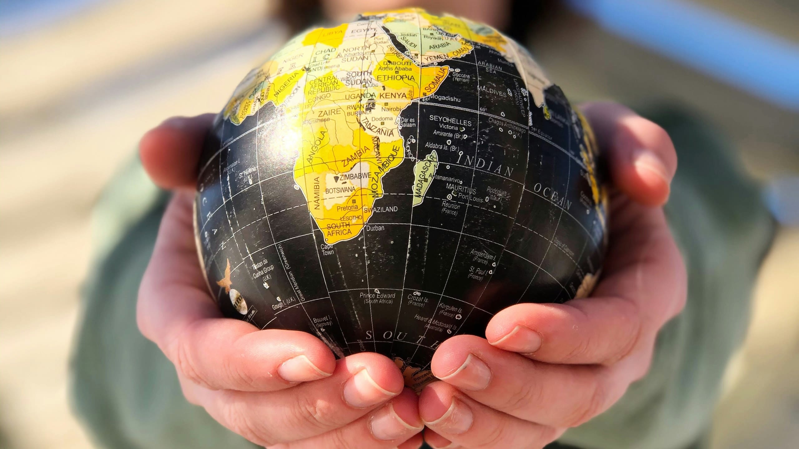 Two hands holding a small globe
