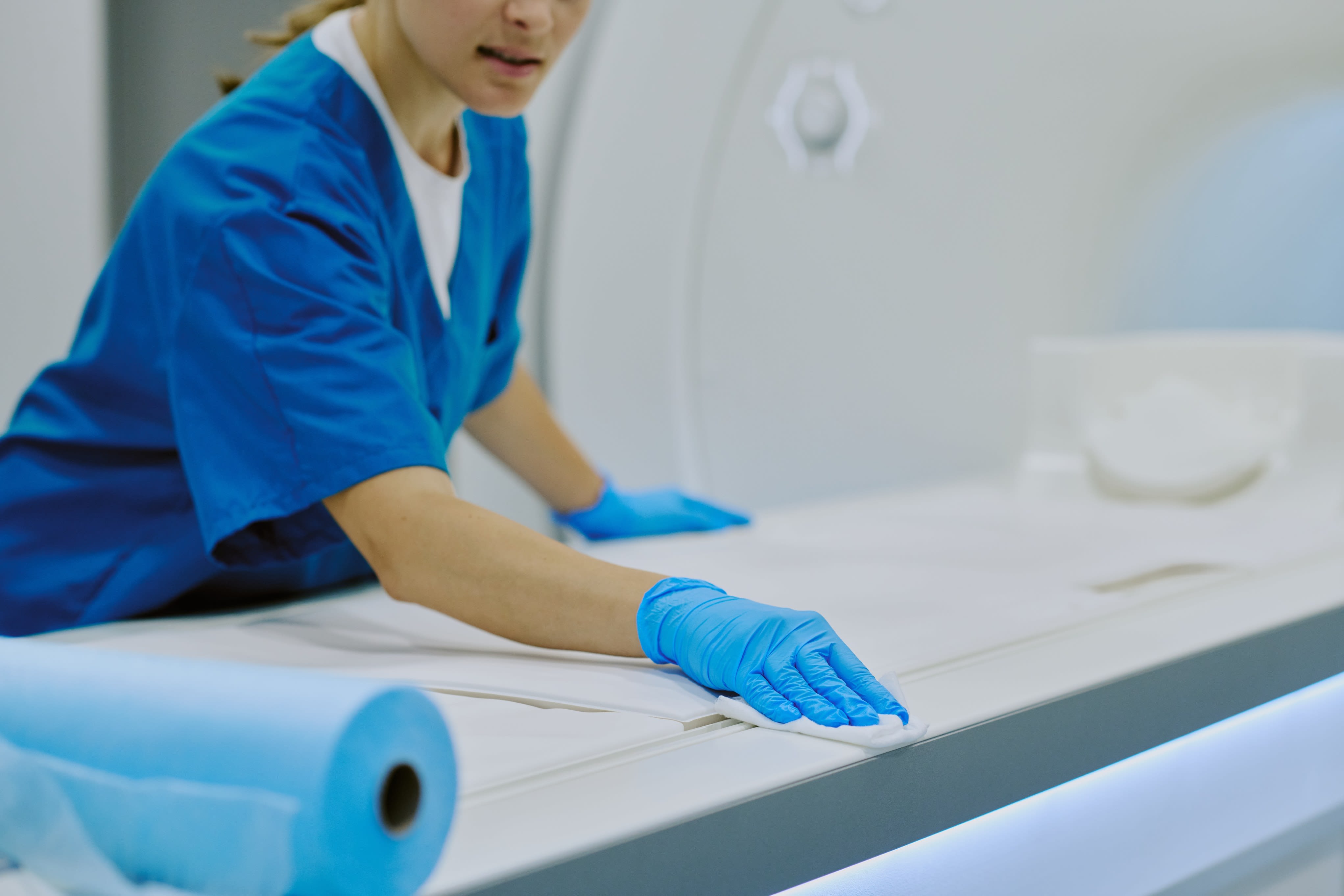 A healthcare professional sanitising a scanner bed
