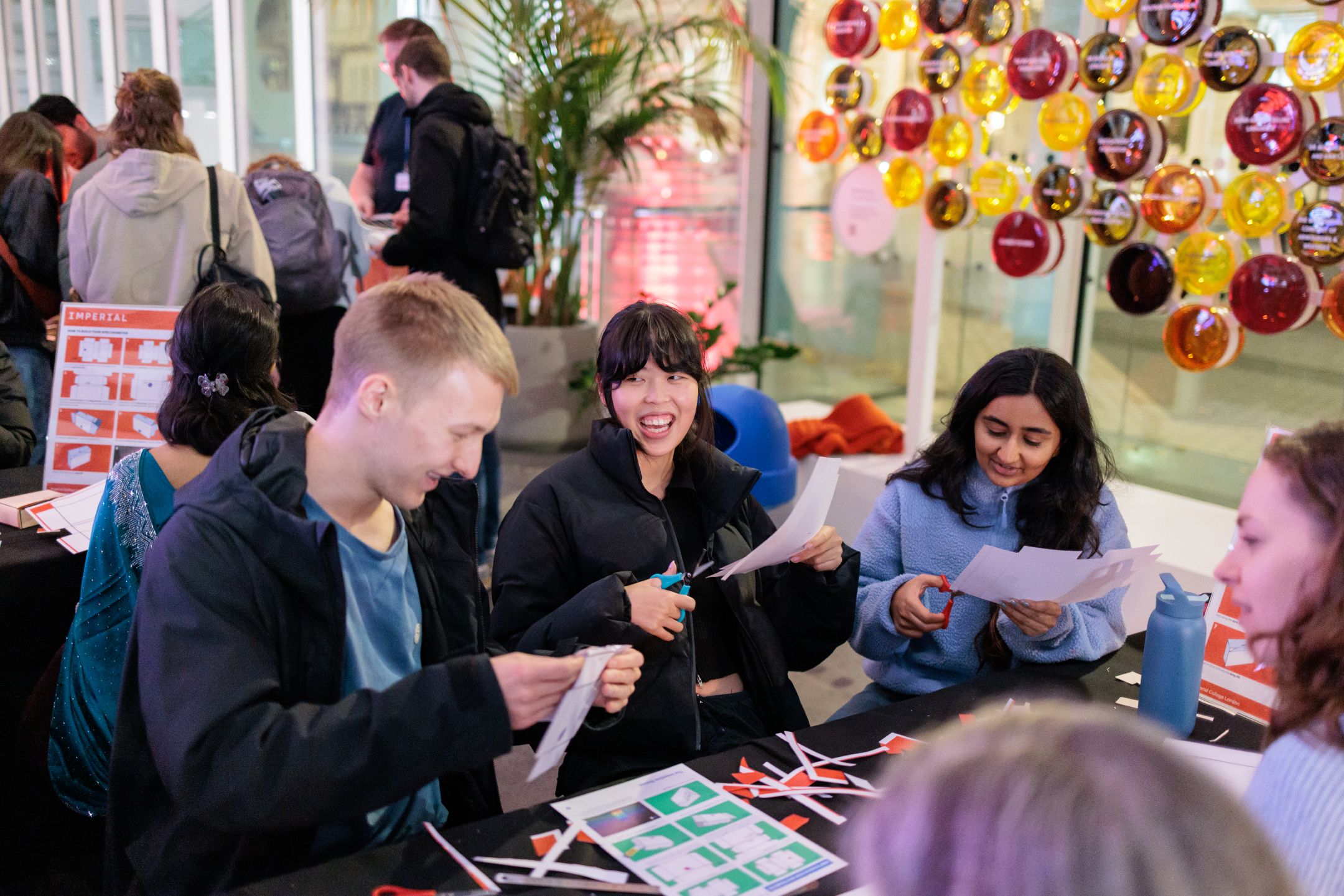 Three people engaging with an exhibit at Imperial Lates