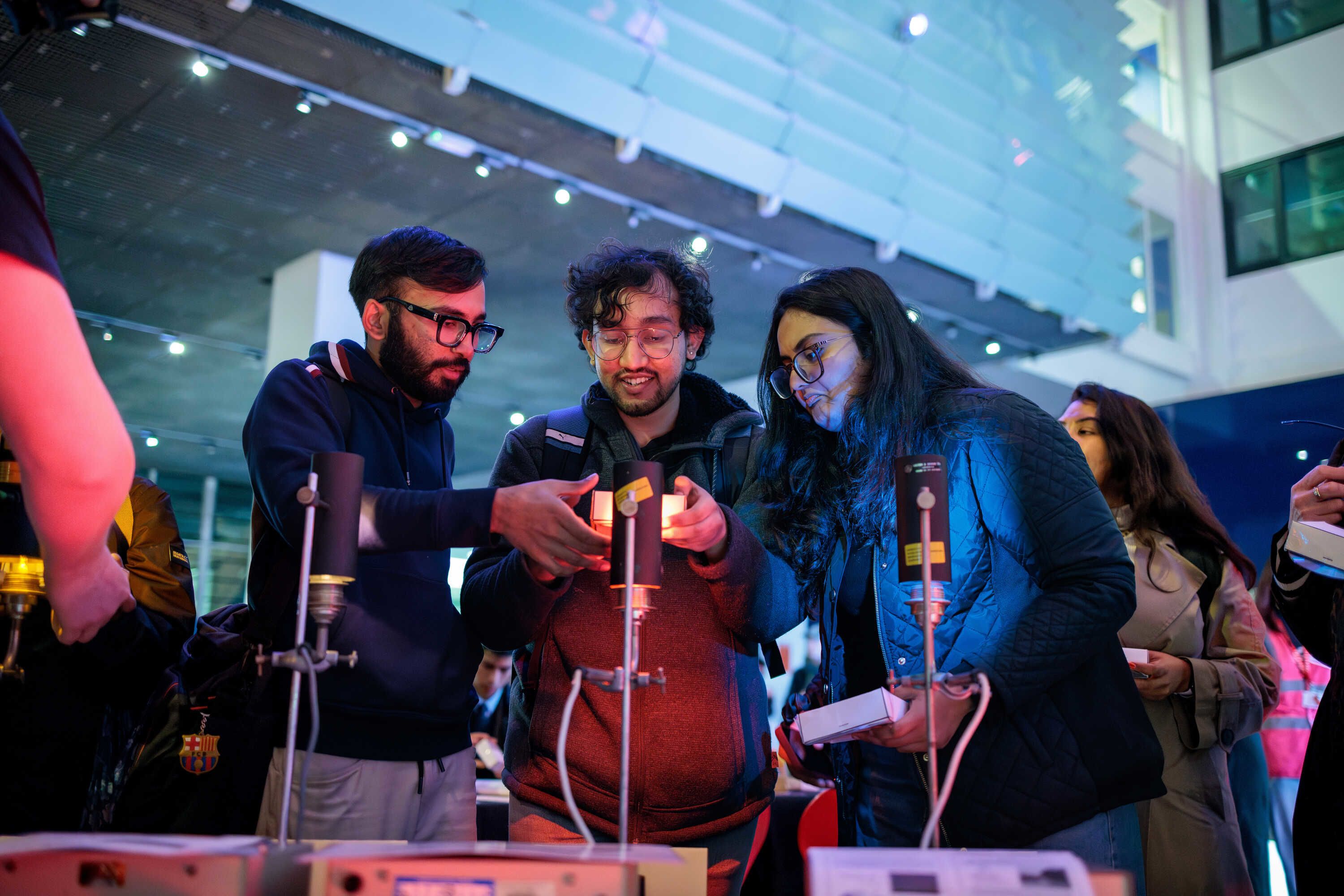 Three people engaging with an exhibit at Imperial Lates