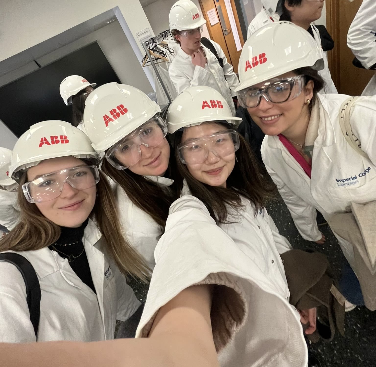 A selfie including Alexandra and three other classmates, all dressed in white lab coats, safety goggles and white hard hats
