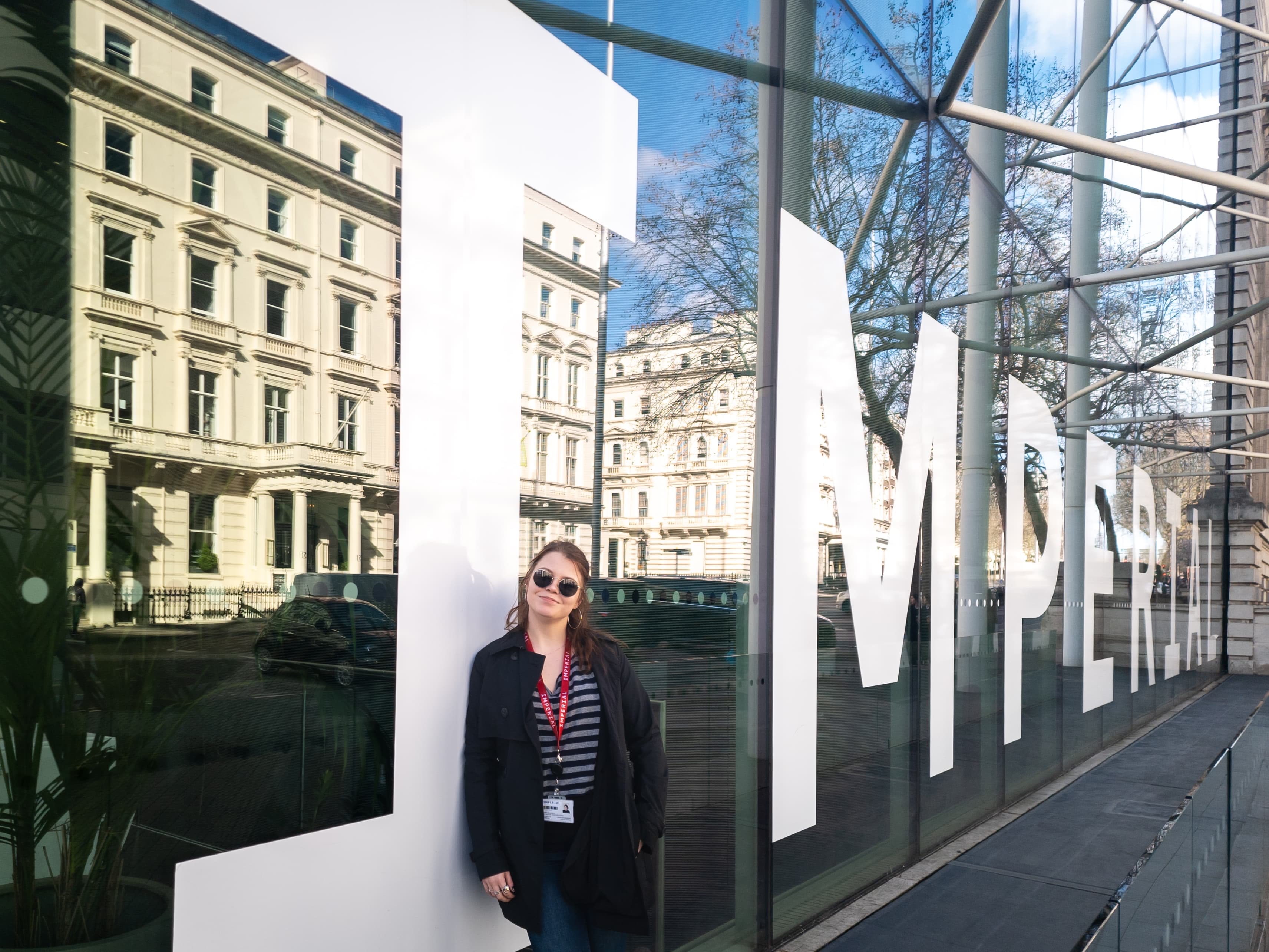Anita standing next to a big glass window with an Imperial logo