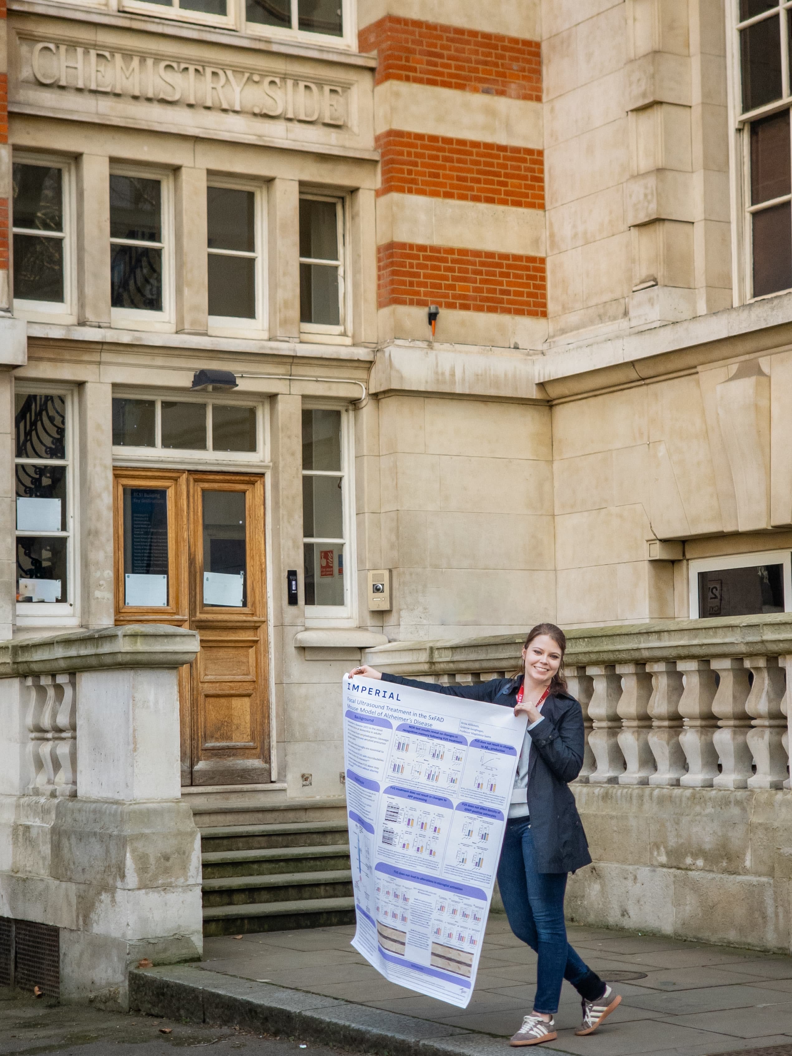 Anita holding a poster showing her research and work outside the Chemistry Building