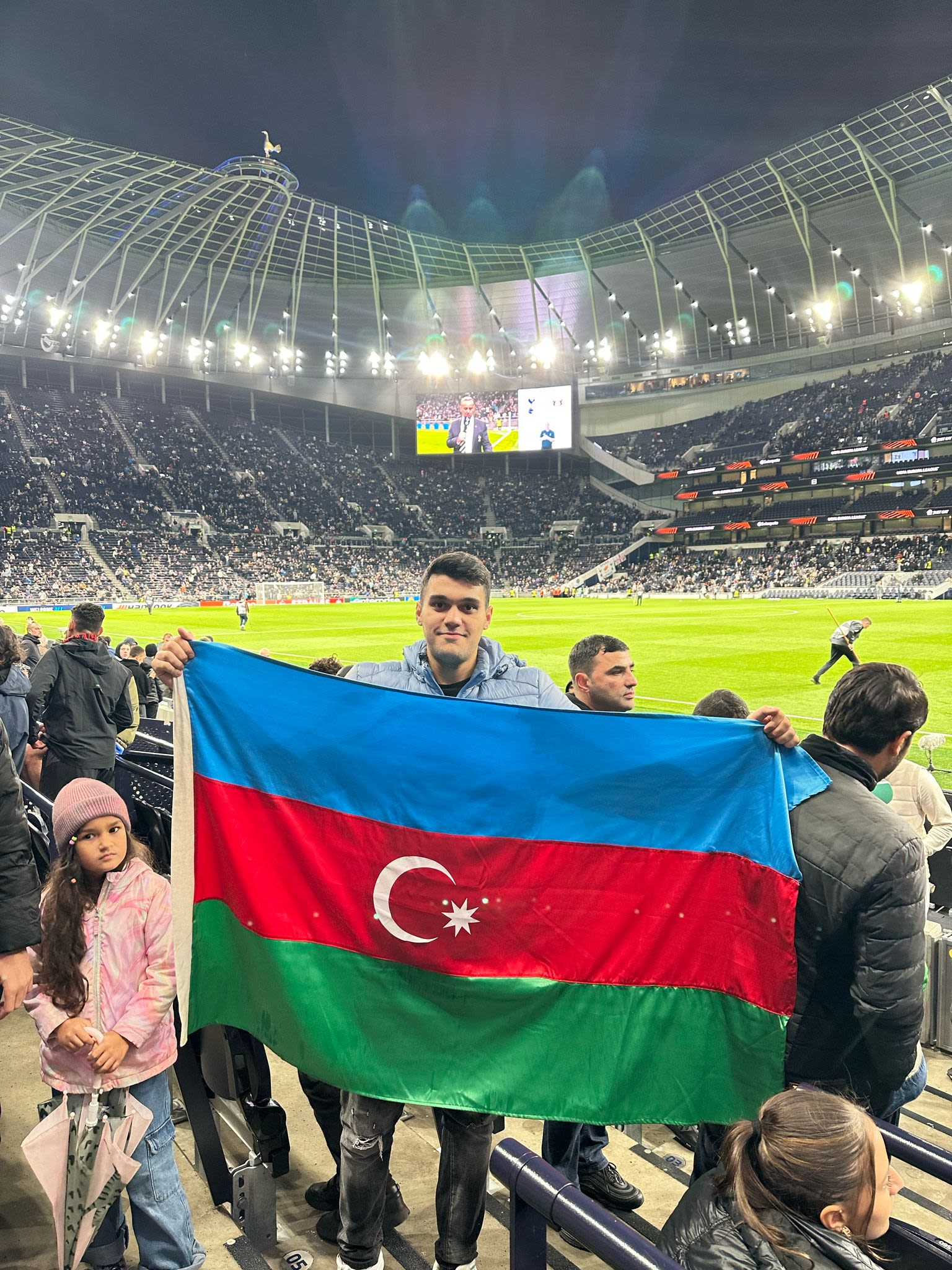 Farid holding a Azerbaijan flag with a football stadium in the background