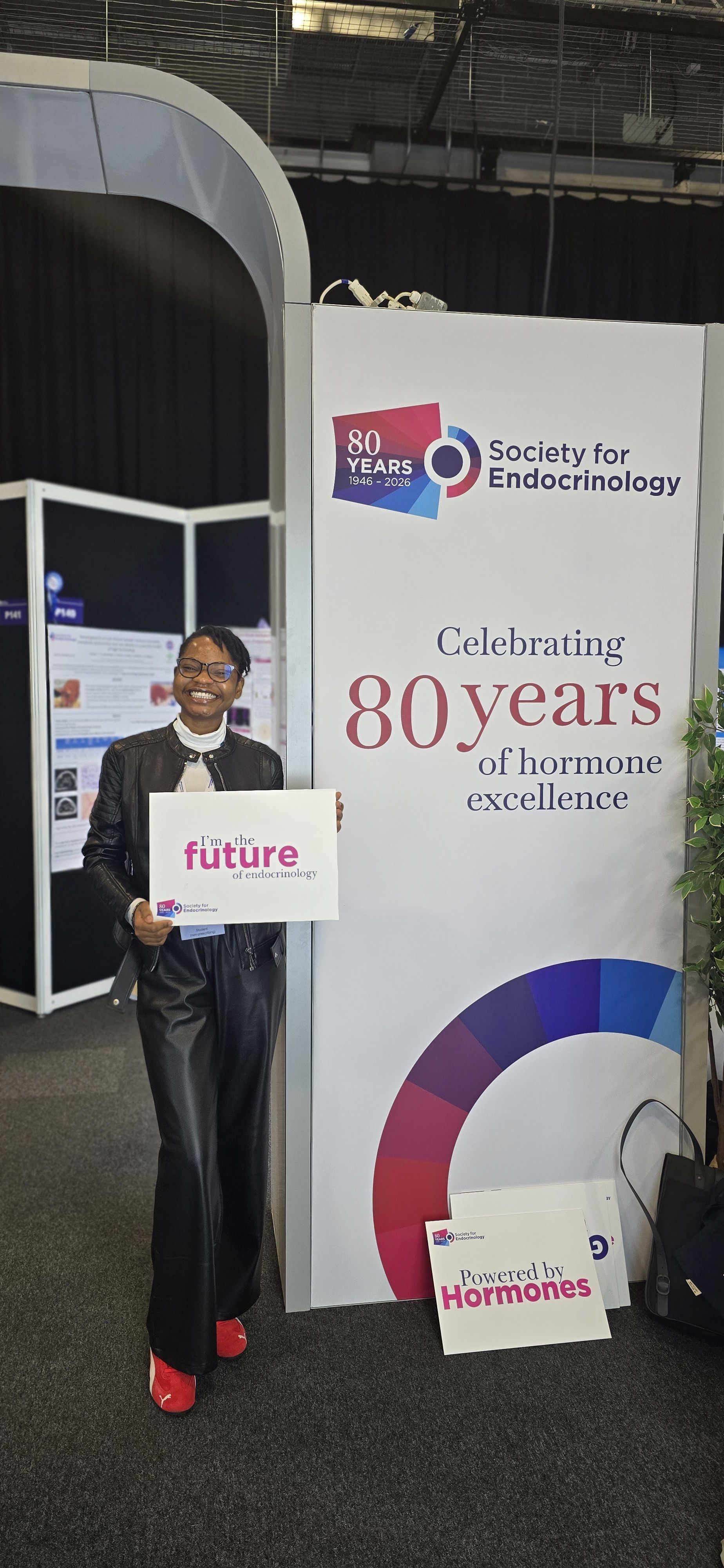 Folakemi holding a sign saying "I'm the future of endocrinology" at an event