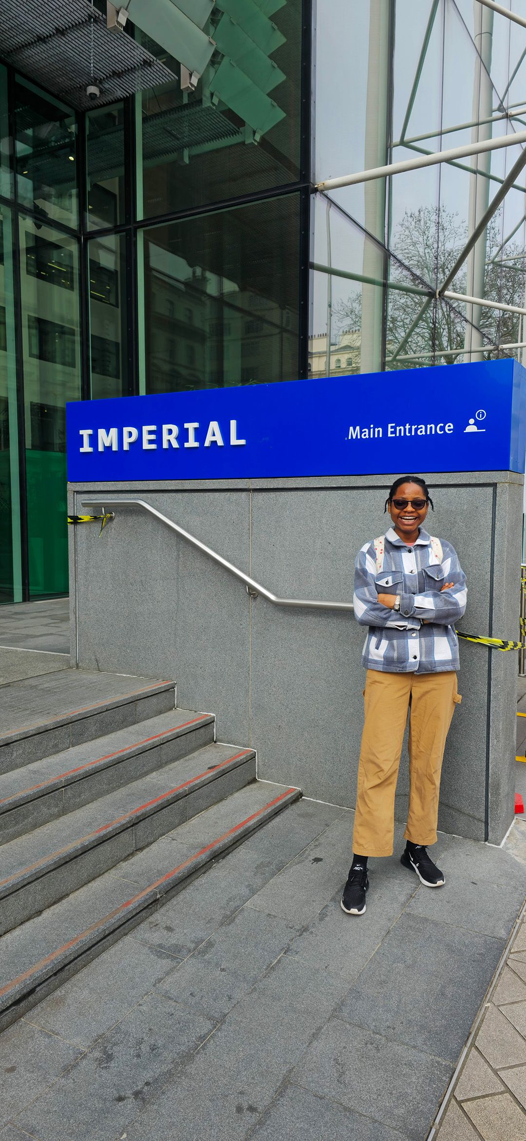 Folakemi smiling and standing by an Imperial logo