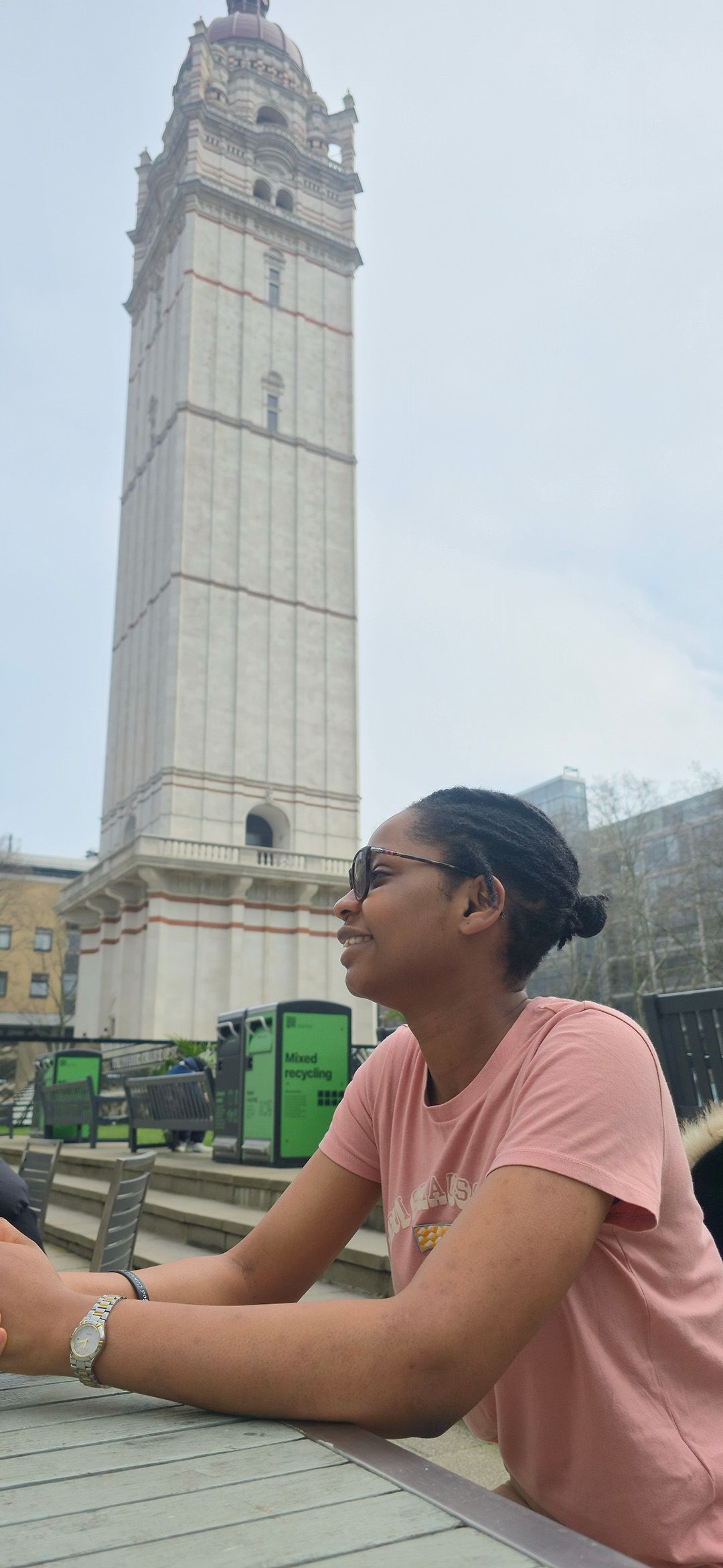 Folakemi sat outside on a bench with Imperial's Queen's Tower in the background