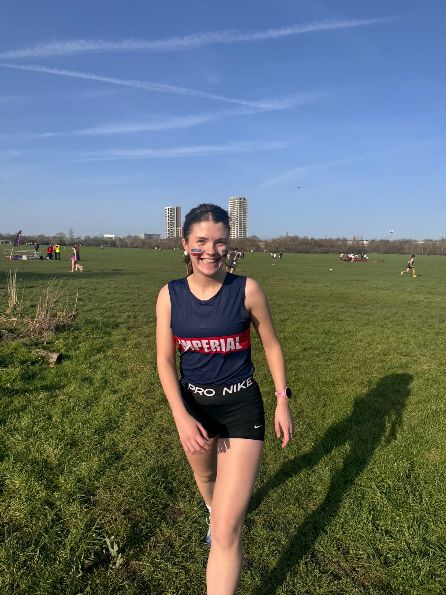 Hannah standing on a grass field wearing an Imperal brandes sports vest and with red and blue striped facepaint