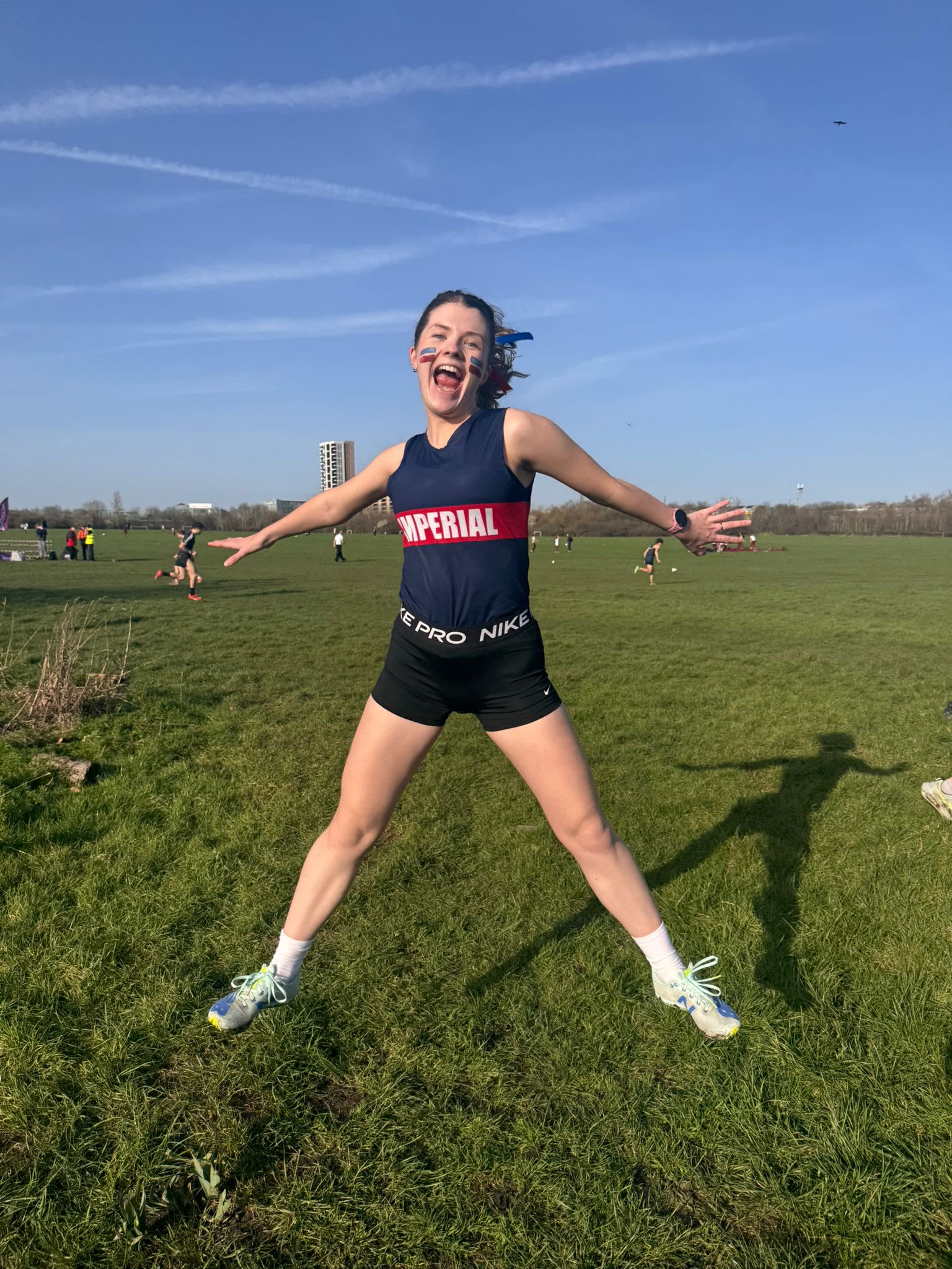 Hannah jumping in the air wearing an Imperial branded sports vest and shorts