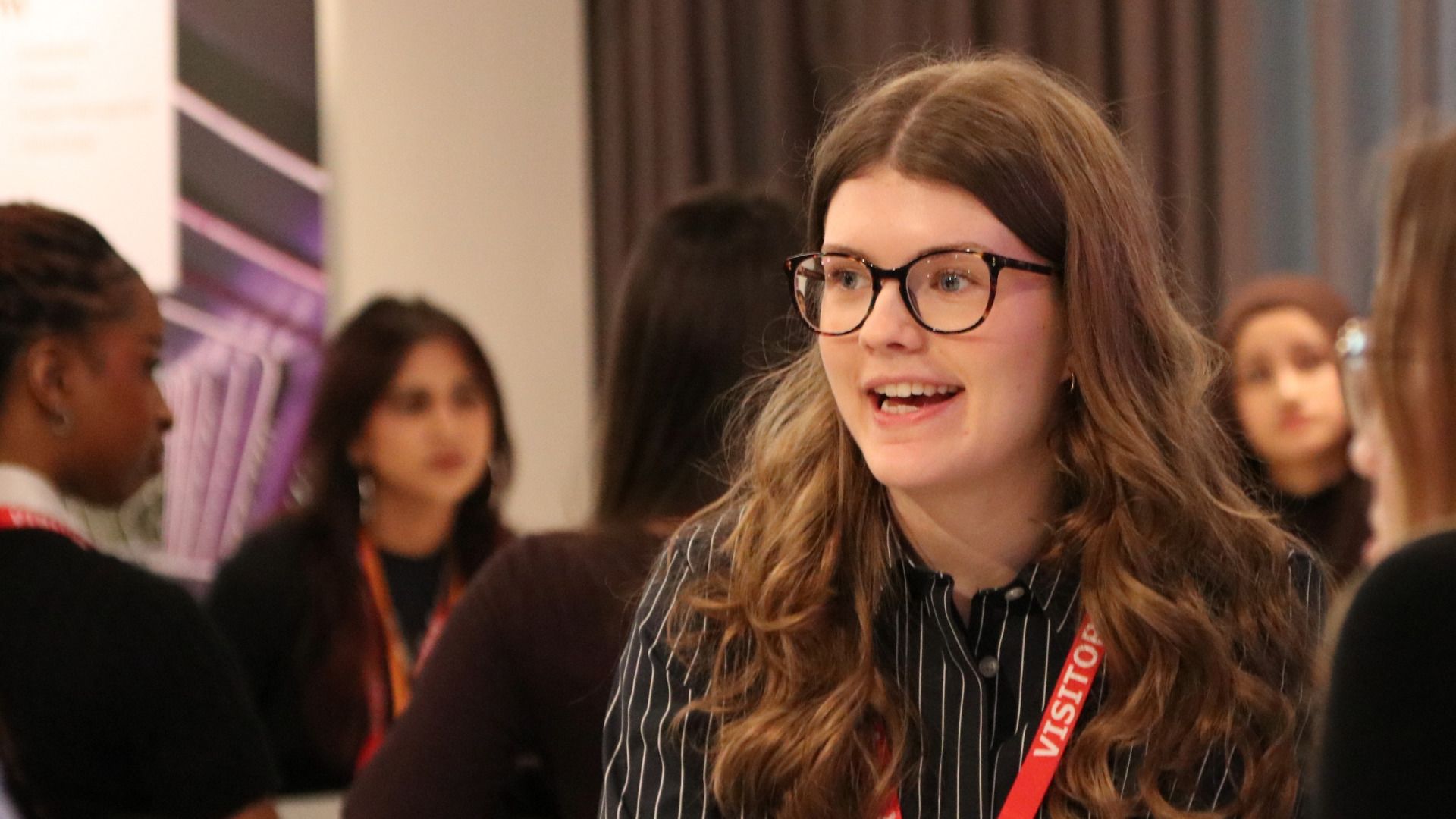 Hannah wearing glasses talking to other students at a round table