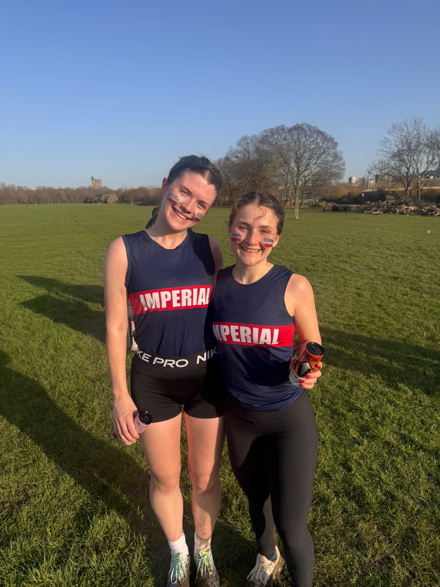 Hannah with another woman, both wearing Imperial branded running vests and with blue and red stripes facepaint
