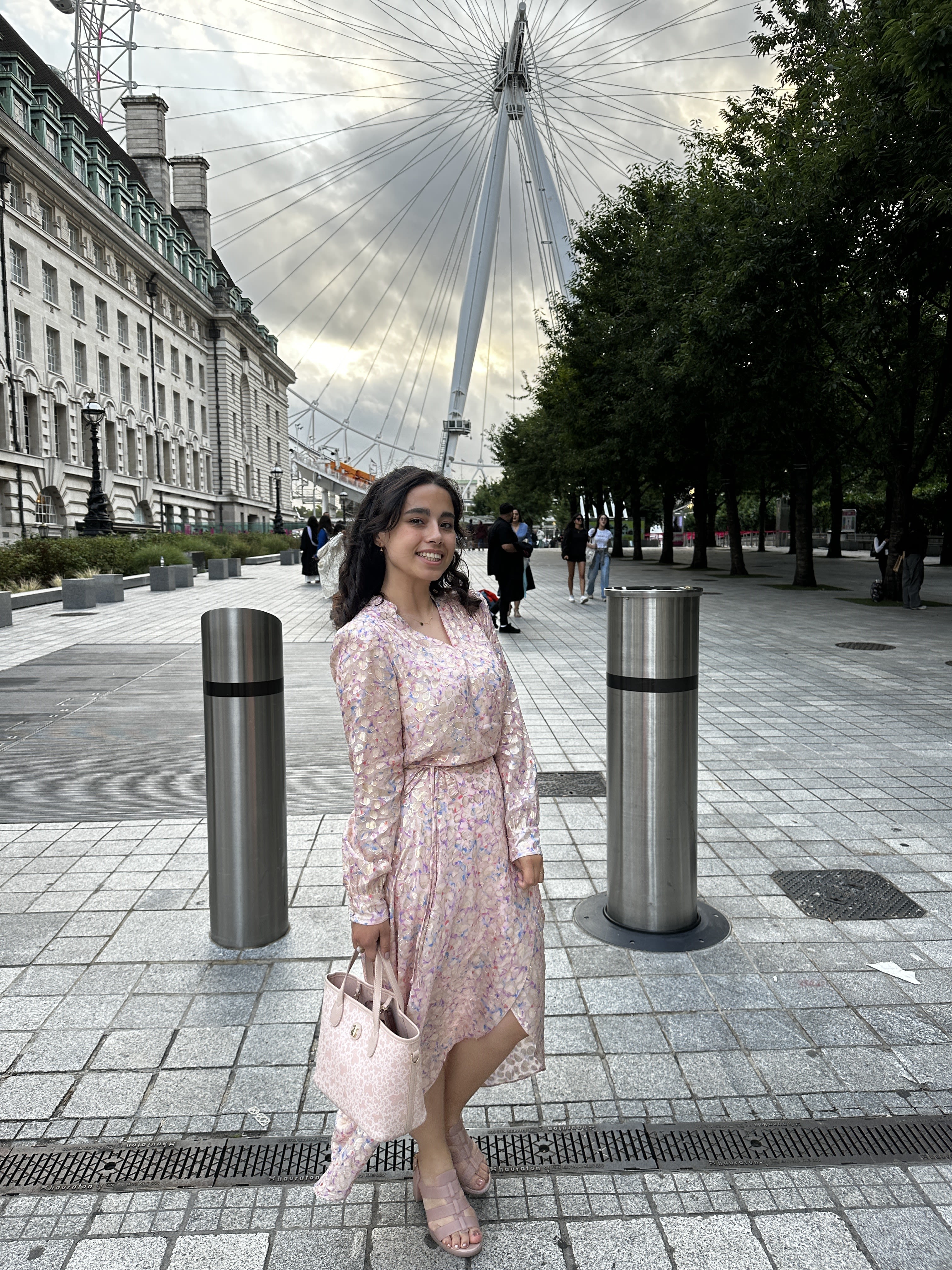 Julia wearing a pink dress and posing in front of the London Eye