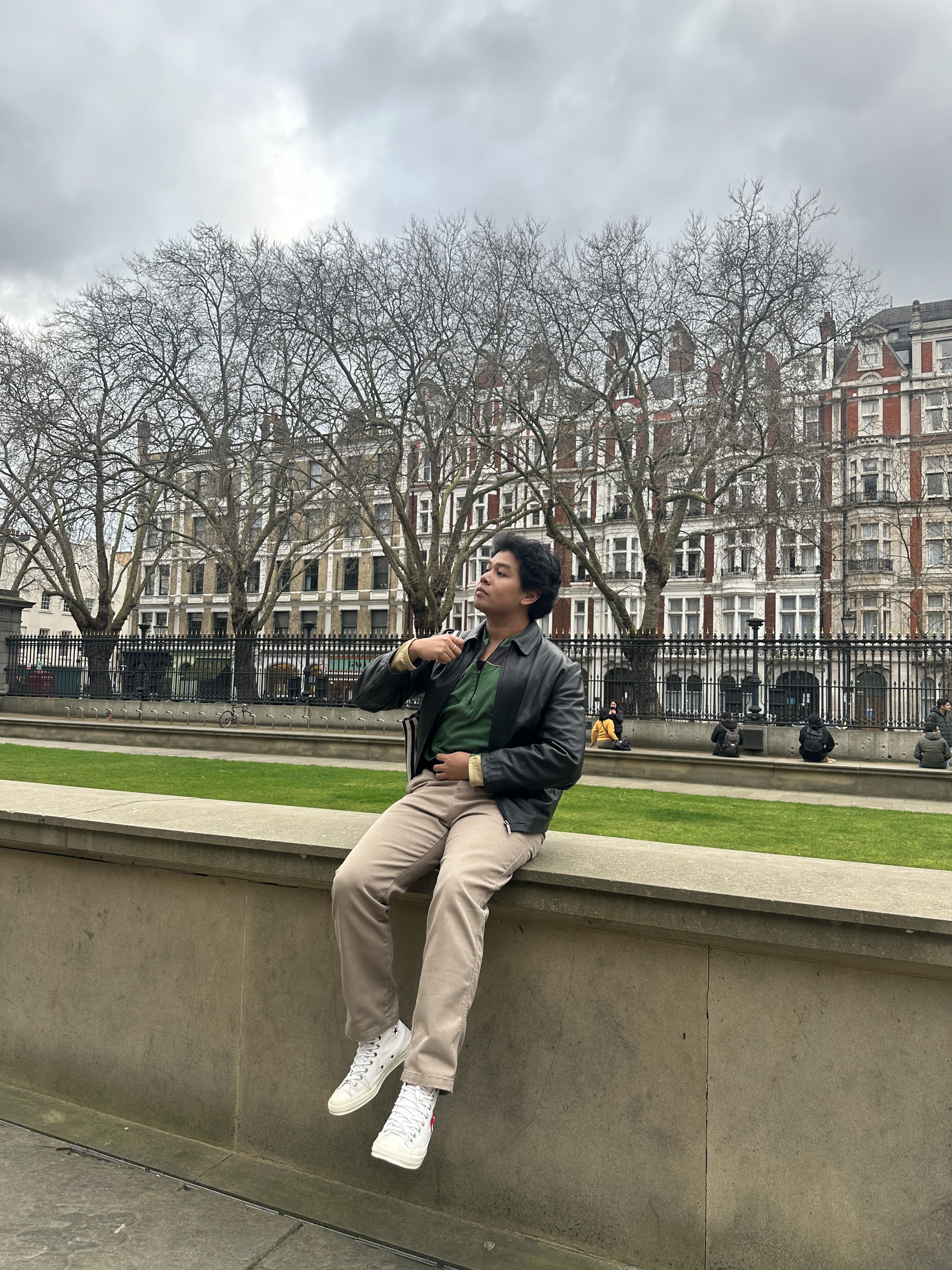 Worapon sitting on a wall outside in London