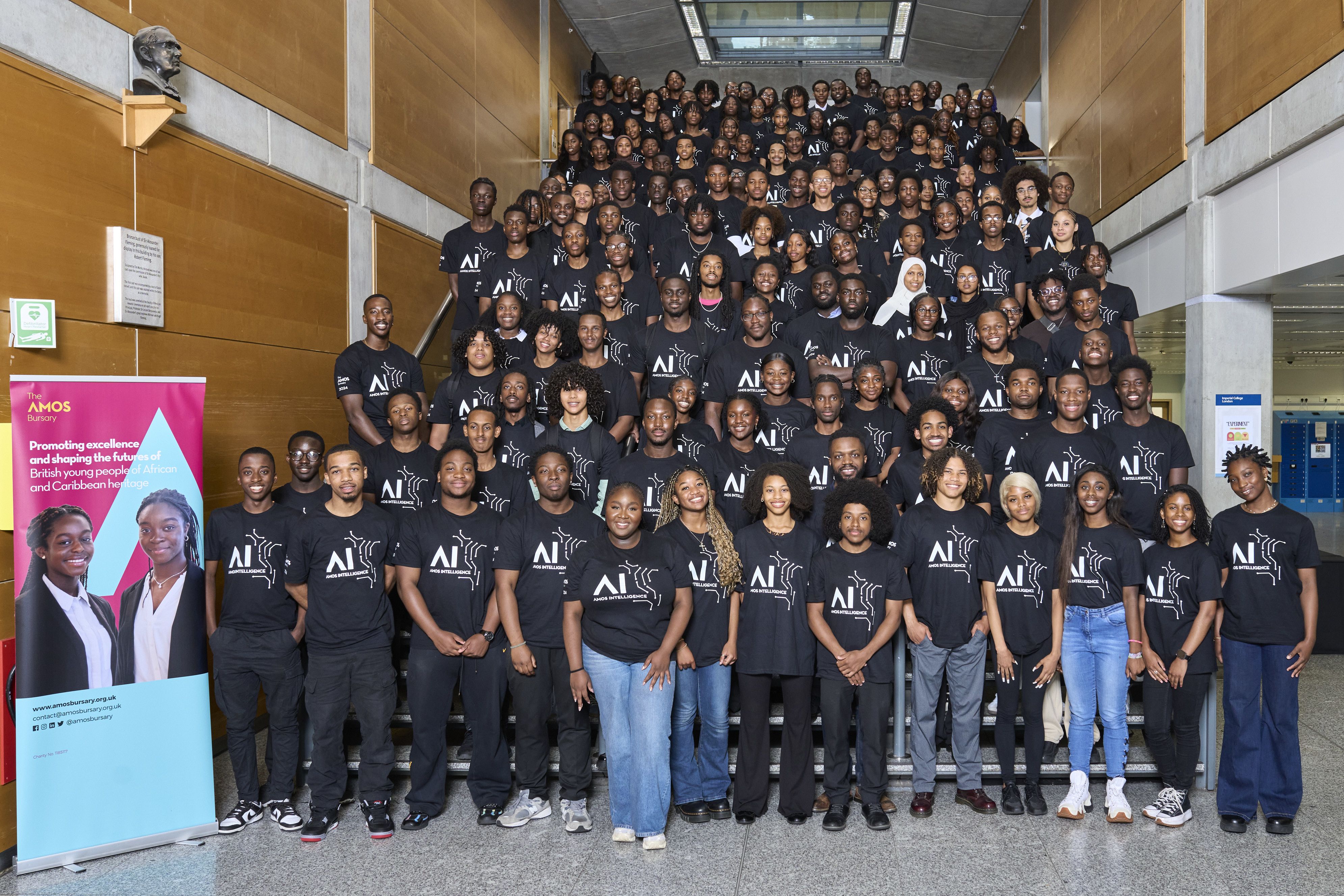 A group photo of 100-200 young people on some stairs wearing matching Amos Bursary T-shirts