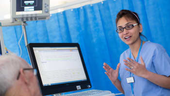 A healthcare worker at a hospital bedside.