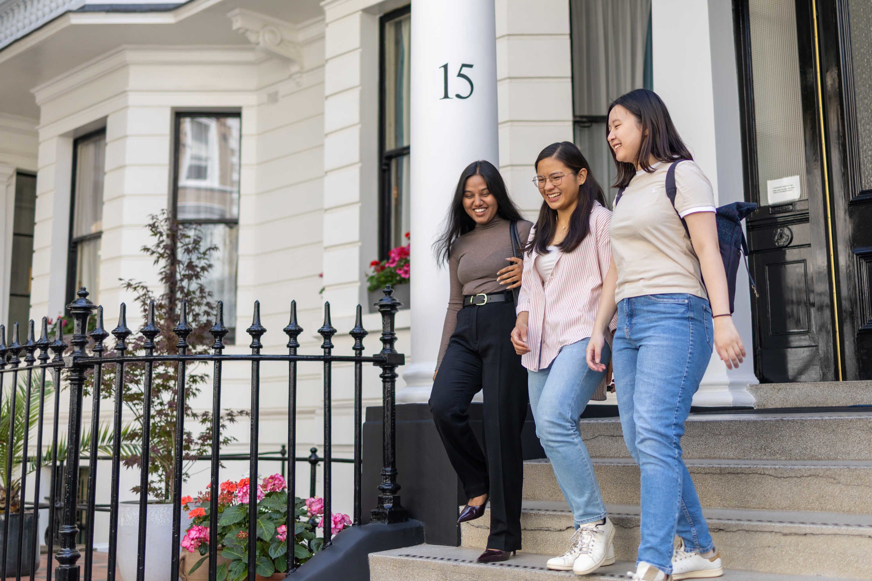 Three students walking down some stairs out of a residential building