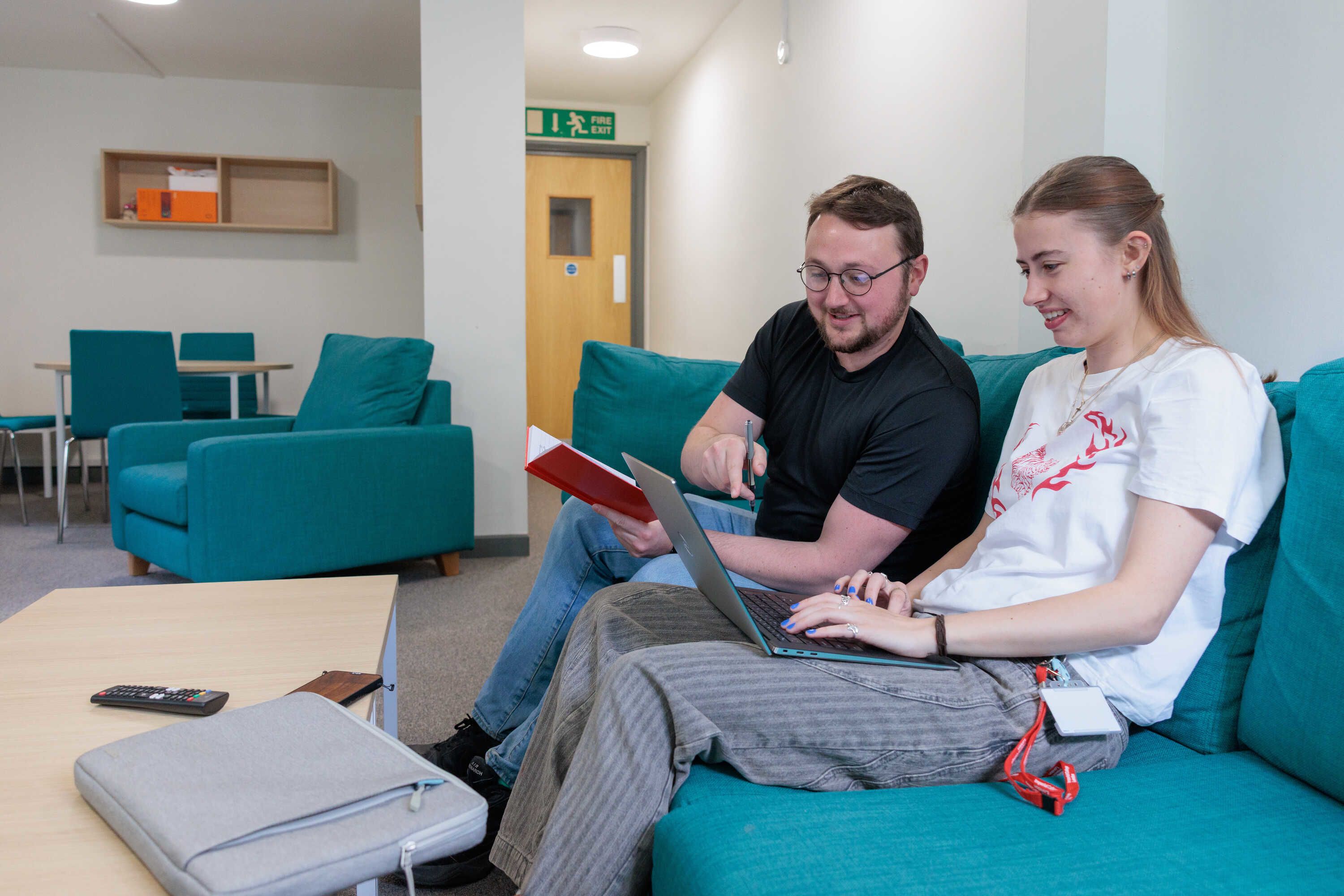 Two students sitting together on a couch looking at a laptop