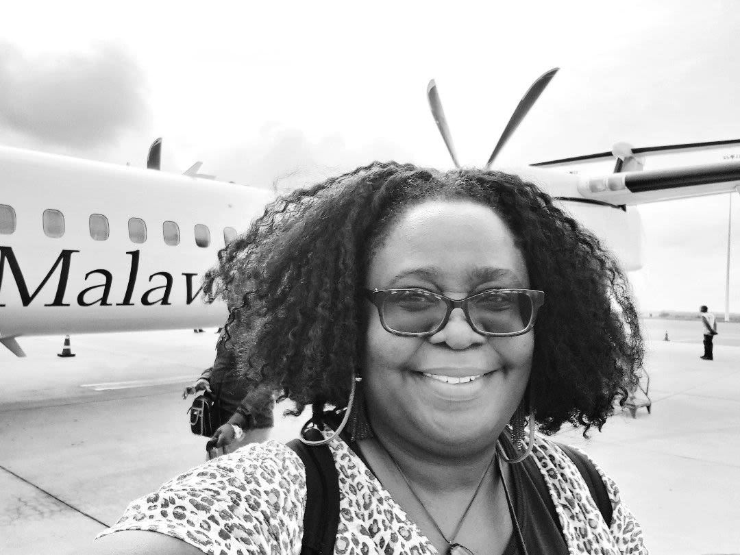 Dr Kibirige by an aeroplane with Malawi written on it.