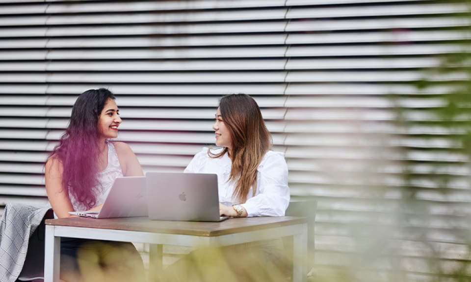 Two Imperial students studying in the courtyard with laptops