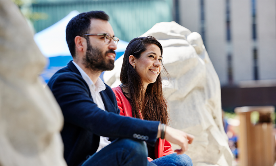 Two Imperial students sitting between the lions near the Queen's Tower