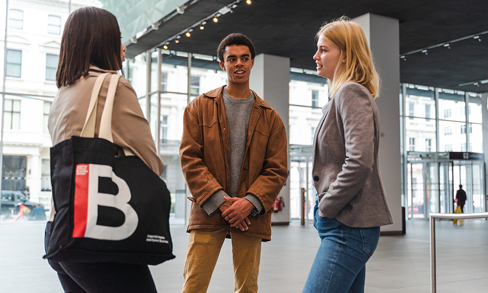 Three Imperial College Business School students standing in the atrium of the College