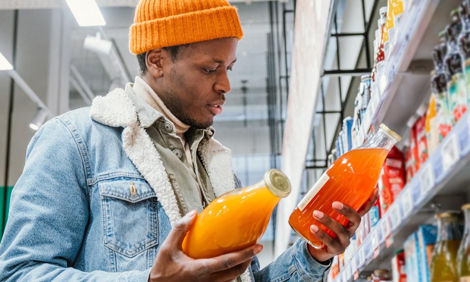 A man in a supermarket looks at two different brands of bottled drink