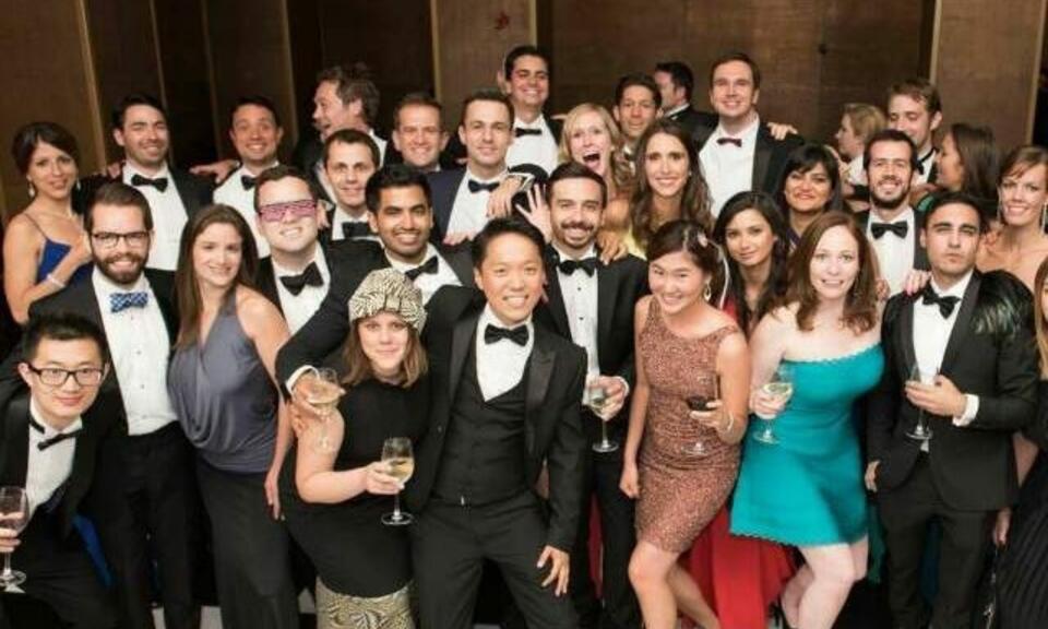 Group of alumni dressed in formal wear posing for a group photo