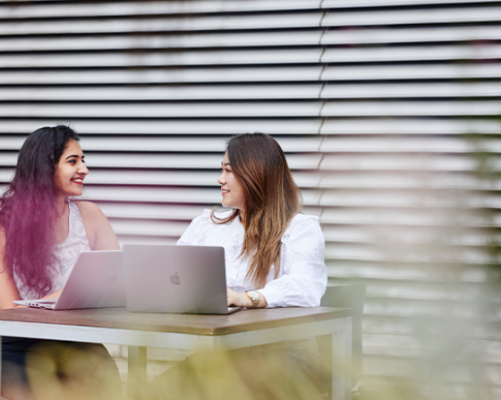 Two Imperial students studying in the courtyard with laptops