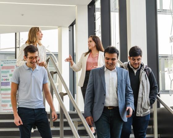 Five Imperial College Business School students walking down a staircase