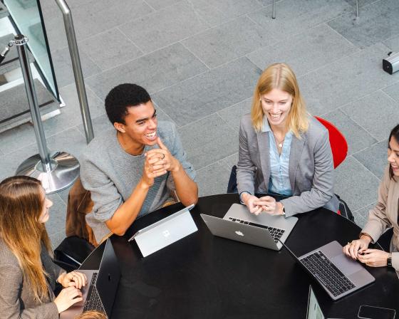 Four students sitting round a table on laptops at Imperial College Business School