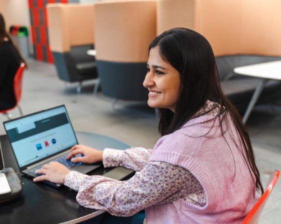 Imperial College Business School student sitting at a table, working on a laptop