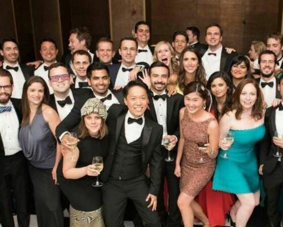 Group of alumni dressed in formal wear posing for a group photo