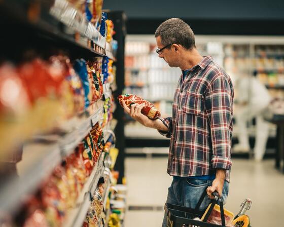 Man reading a label while grocery shopping in a supermarket aisle