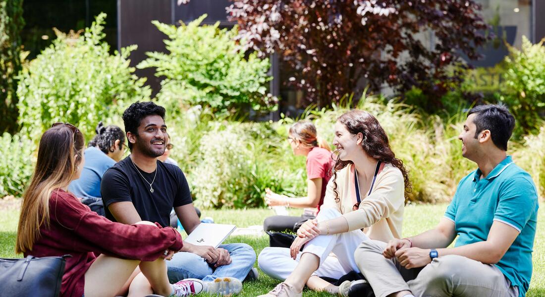 Four students sitting in Queens garden