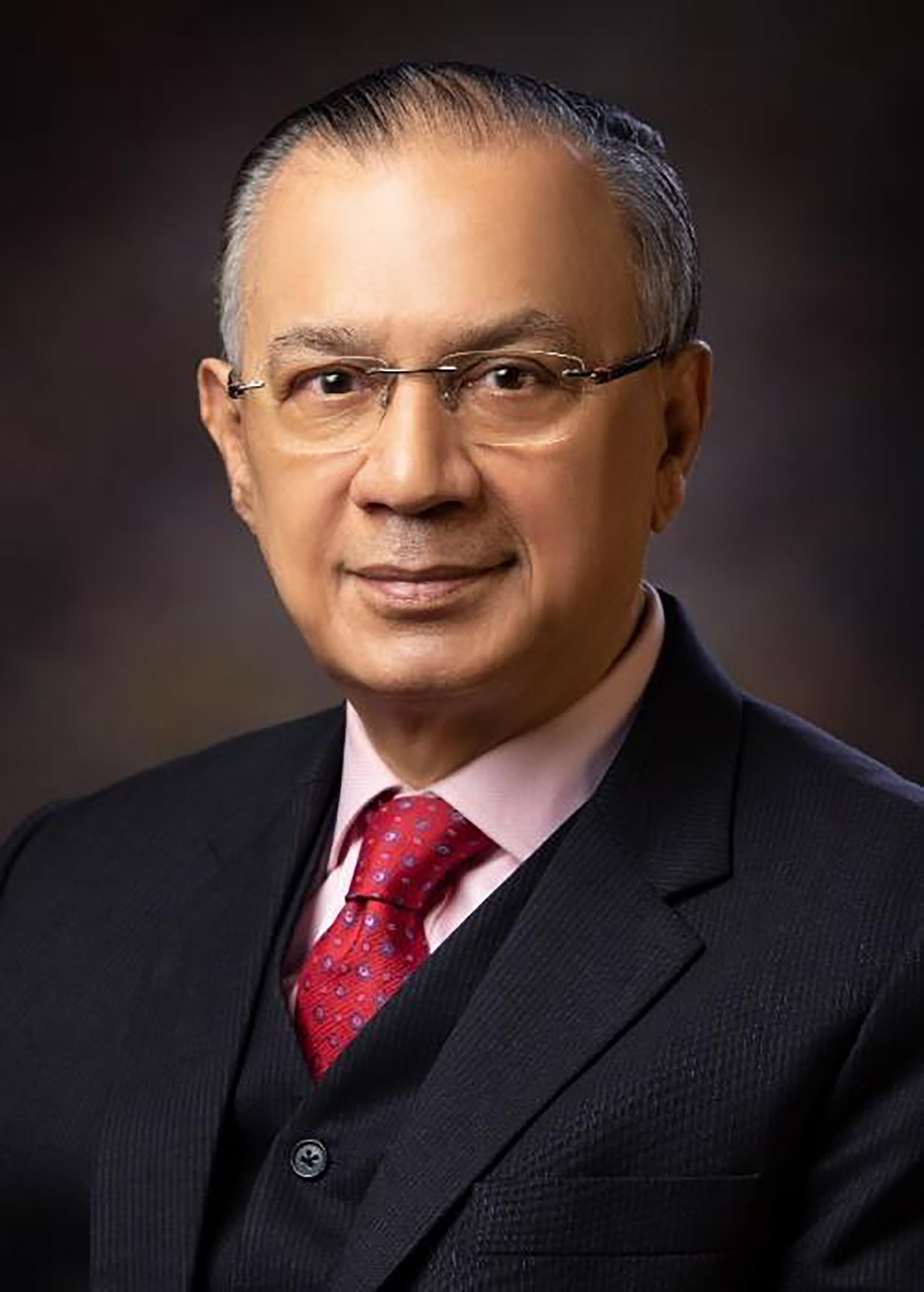 Headshot of Dr Hirak Sen wearing a suit, he is posed against a dark background