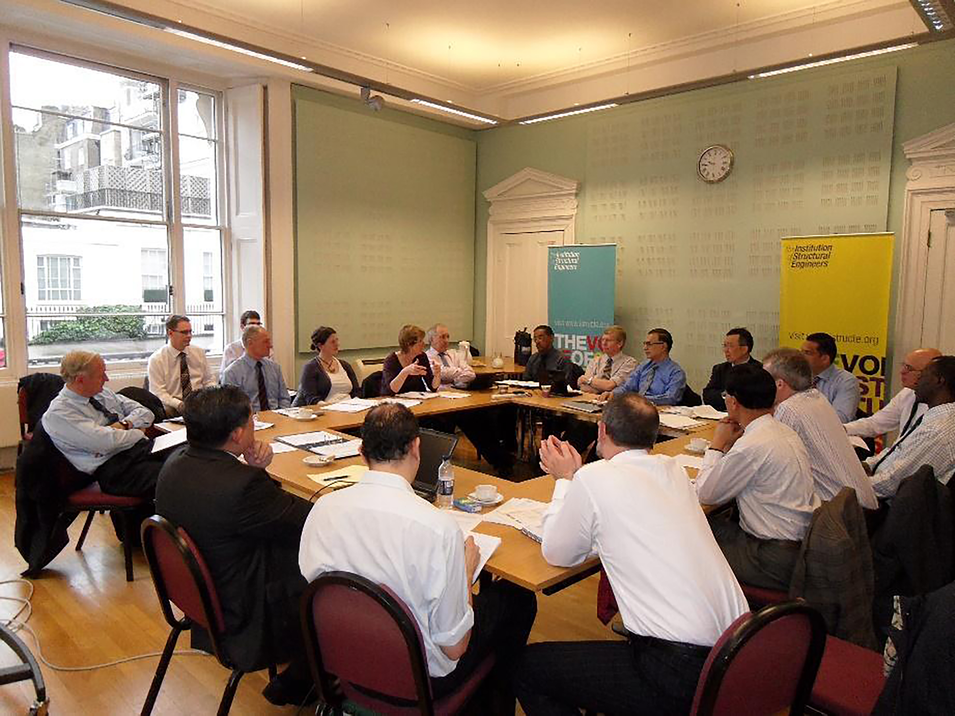 Dr Hirak Sen pictured around a large horseshoe shaped table in a mint green meeting room lit with artificial lighting