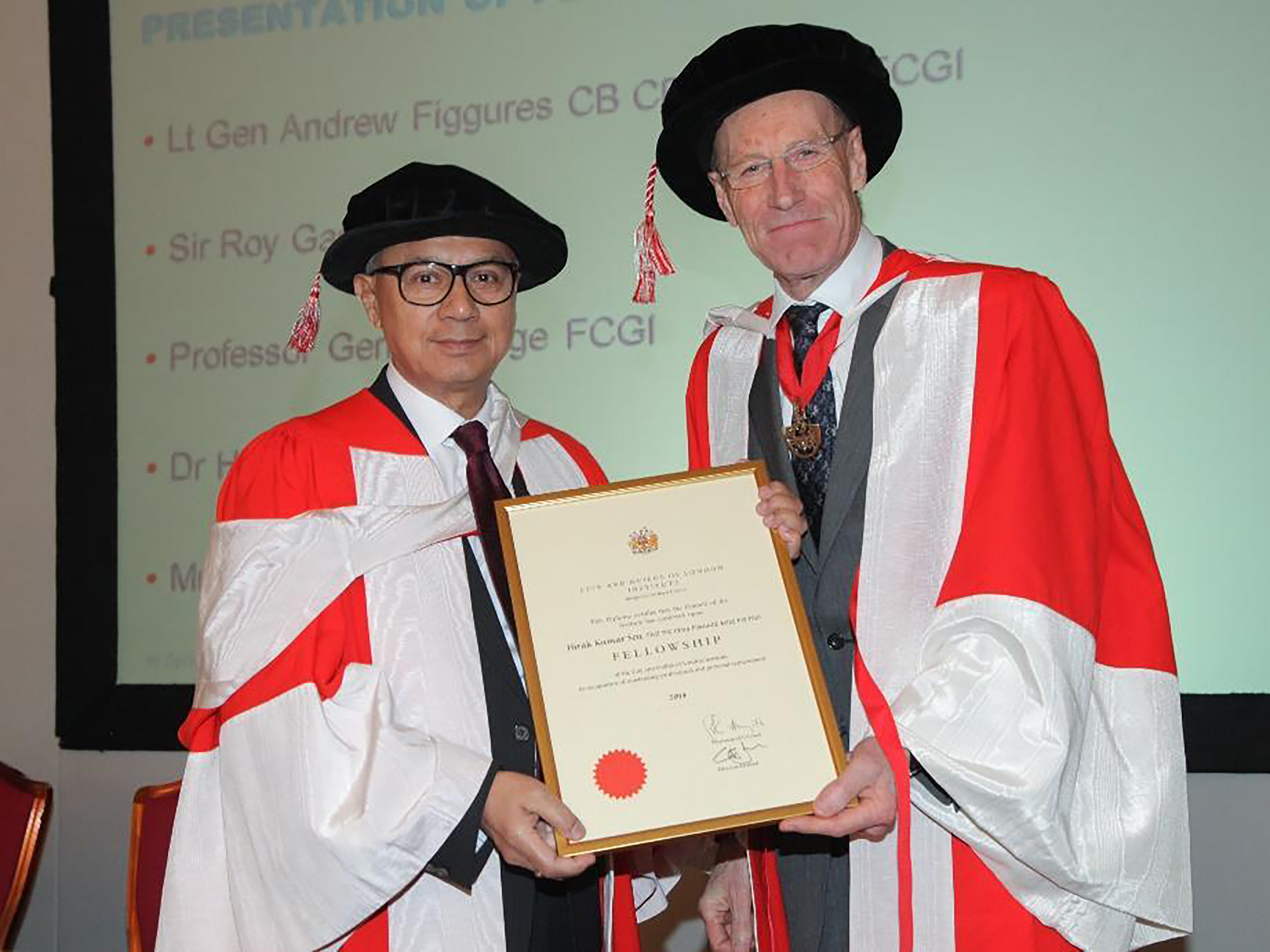 Hirak wearing a formal red/white gown and gap receiving the Fellowship award