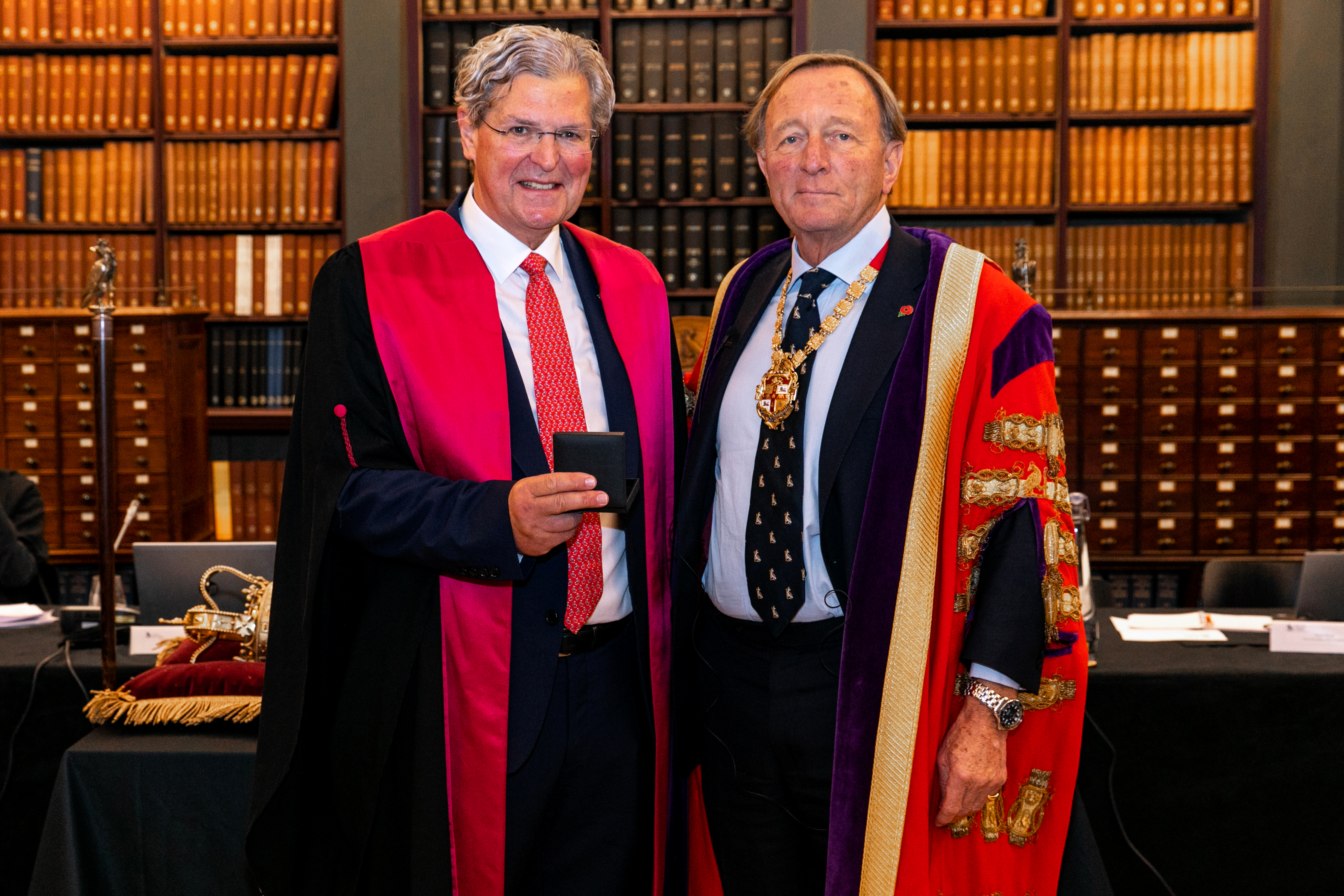 Merv the President of Royal College of Surgeons - Professor Neil Mortensen. They are wearing traditional gowns and standing side by side. Merv holds the box containing his medal