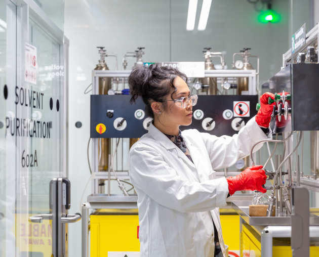 student in lab coat using chemistry equipment