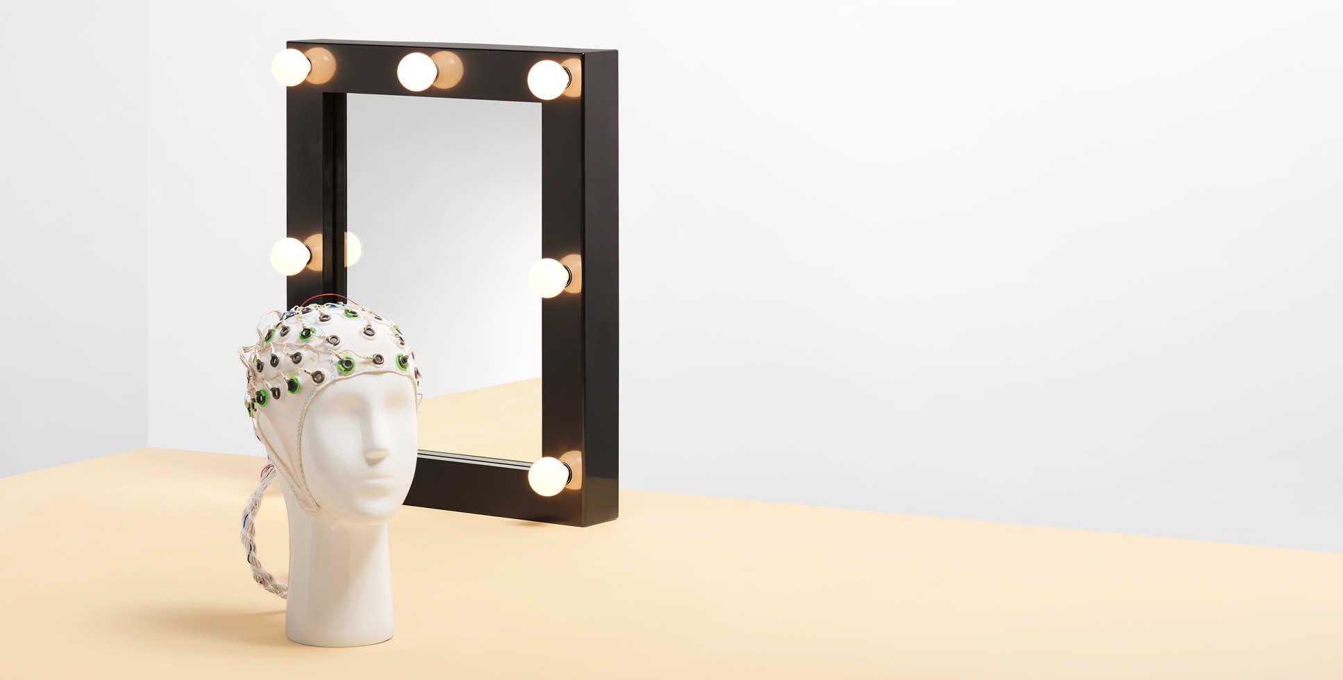 A mannequin of a head fitted with a brain monitor, in front of a mirror