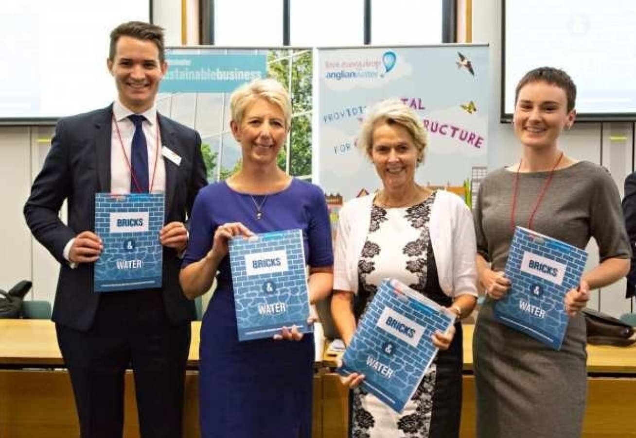 Image of four people holding up Naomi Pratt's report: 'Bricks and Water'