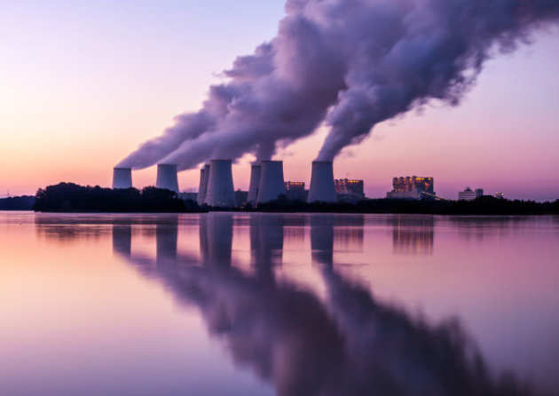 power stations billowing smoke with reflection in the lake in front